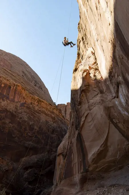 Low angle view of young woman canyoneering on mountain