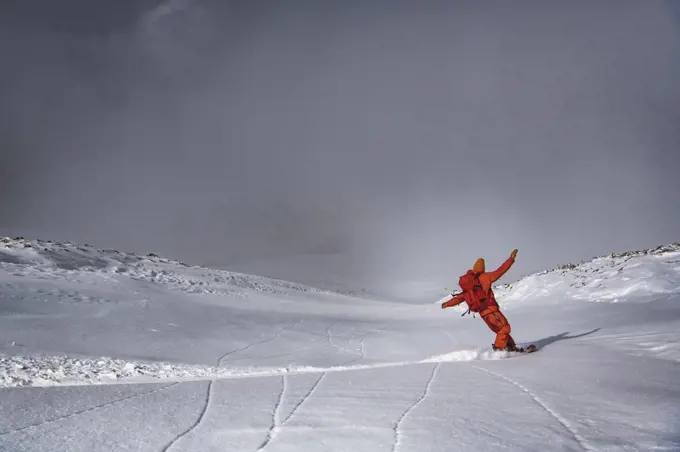 Man snowboarding on mountain against sky during vacation