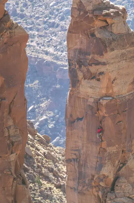 Man climbing rocky cliff at Canyonlands National Park during vacation