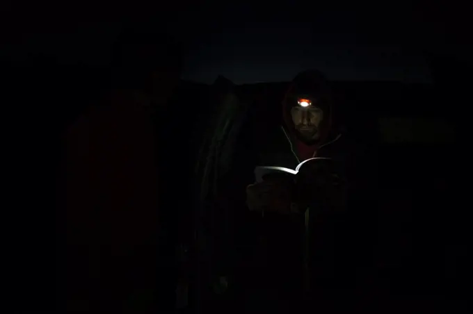 Man reading book with light of head lamp during night at Canyonlands National Park