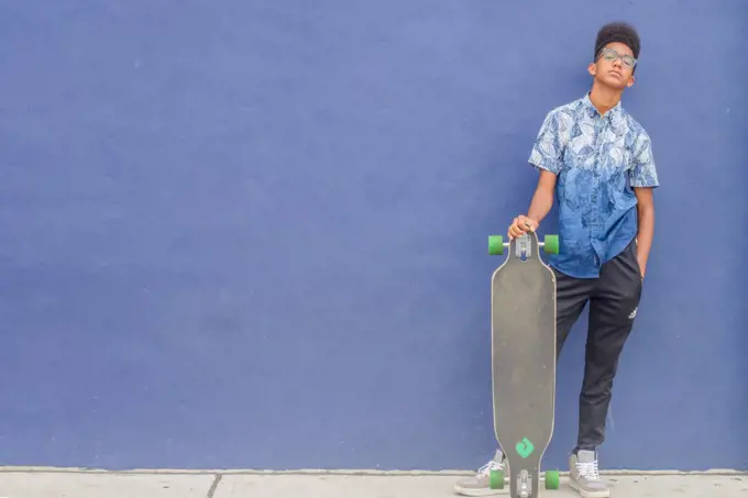 Skateboard teen against blue wall