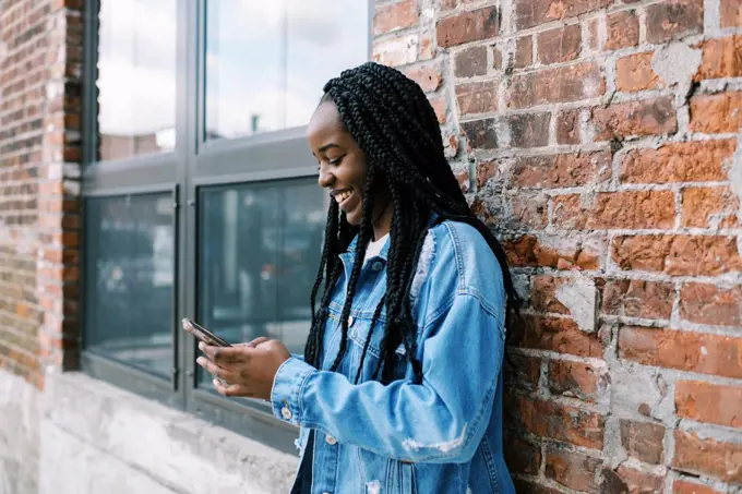 Young black woman scrolling on social media and holding her phone