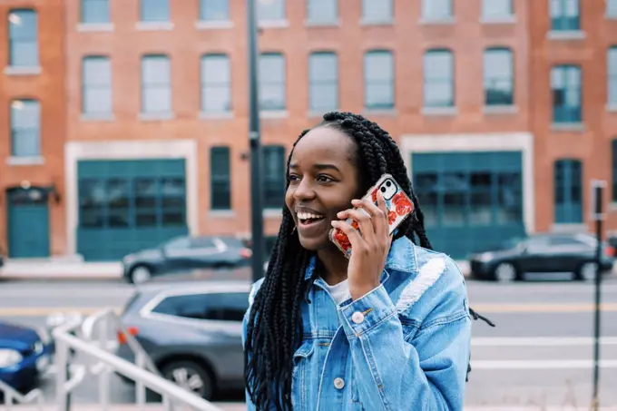 Young black woman using her phone for a call with city surrounding