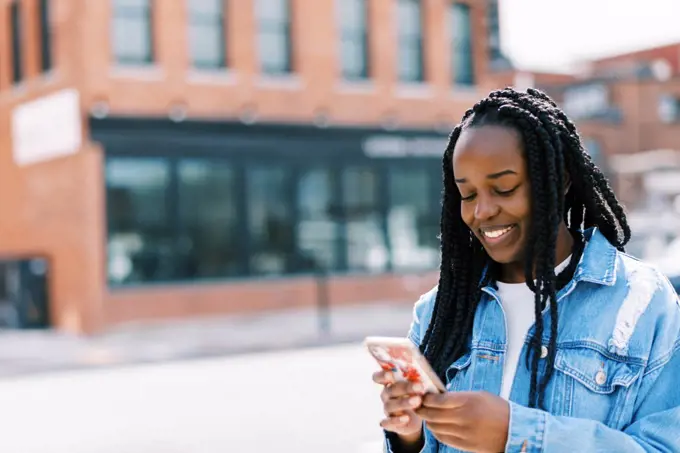 Young black woman scrolling online on social media on phone