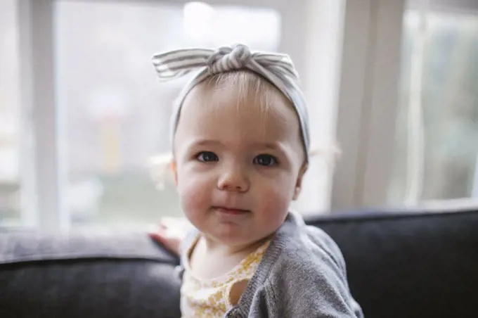 Portrait of cute one year old girl wearing headband inside at home
