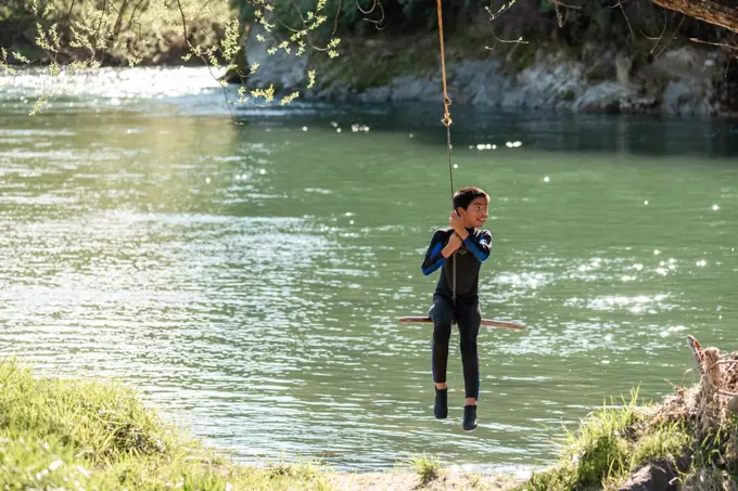 Young teenager on rope swing over river in New Zealand
