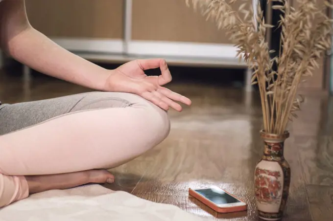 Low section of woman doing yoga in lotus position at home