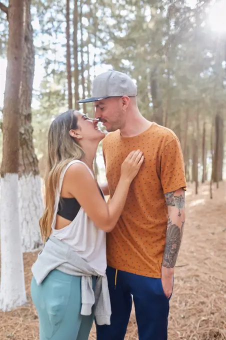 happy engaged couple kissing in the middle of the forest
