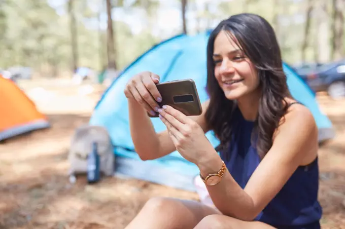 Young Latina woman using her smarthphone outside her tent
