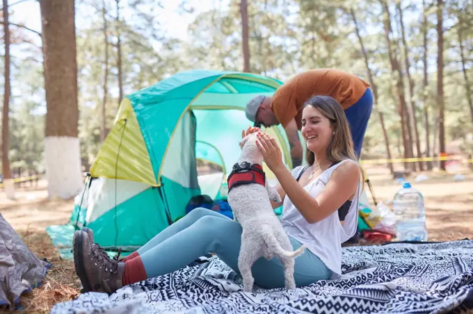 Happy young couple with dog sitting outside the tent