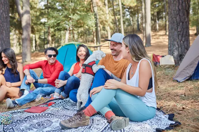 group of friends with their dog having a nice time outside their tent