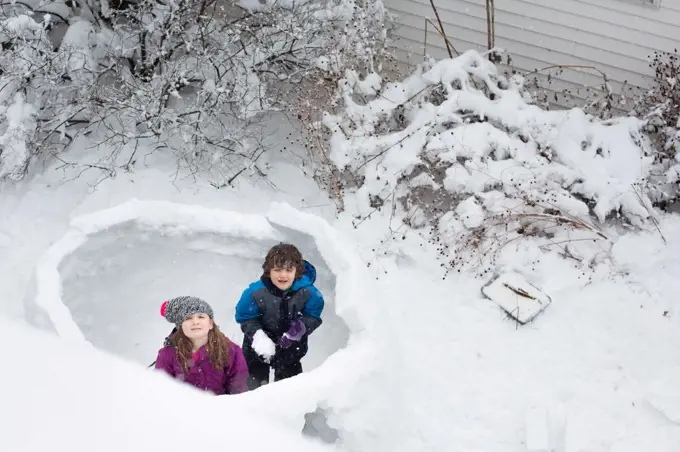 Two children making a snow fort in the winter