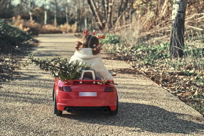a girl in a christmas outfit in her red car