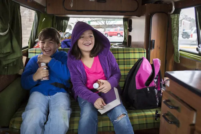 A brother and sister laugh in back of VW camper van during Idaho
