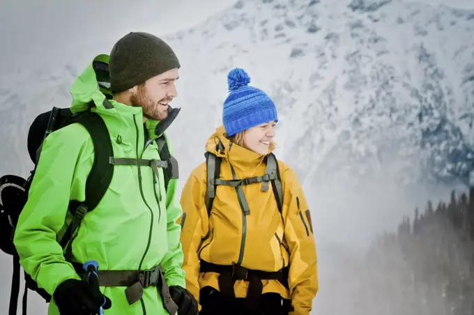 Couple wearing winter jackets in outdoor mountain setting.