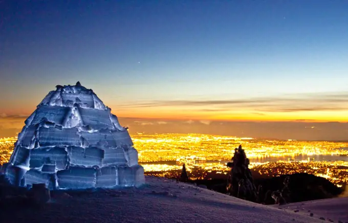 Igloo on mountain summit above city lights of Vancouver, Canada.