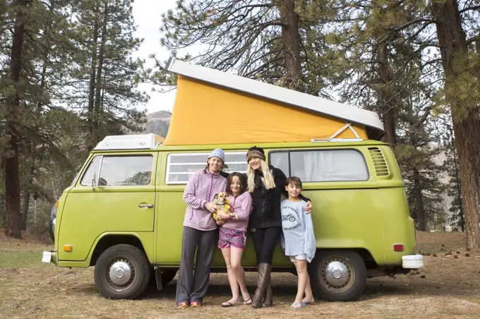 Portrait of two women, two children and dog in front of green VW van