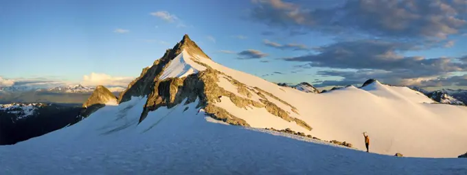 Panoramic view of mountain climber approaching rock mountain summit