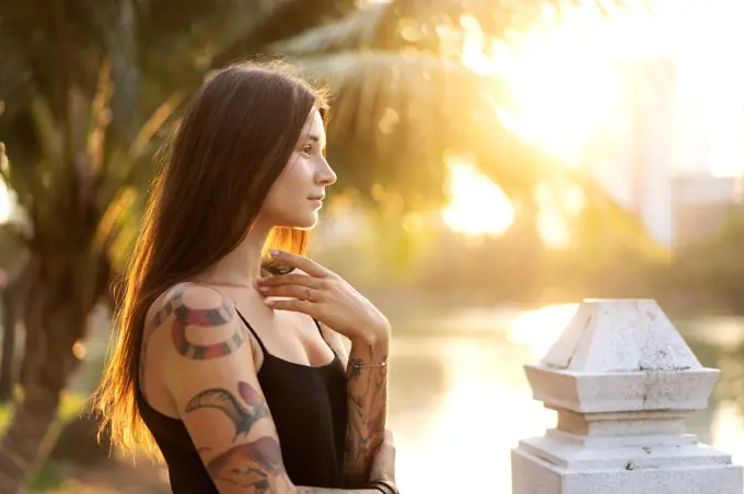 beautiful girl in tattoos among the palm trees at sunset