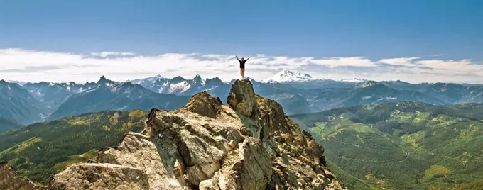 Hiker celebrates hiking to the summit of a rocky mountain, scenic view