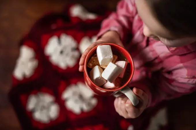 Overhead view of girl driking hot cocoa with marshmallows