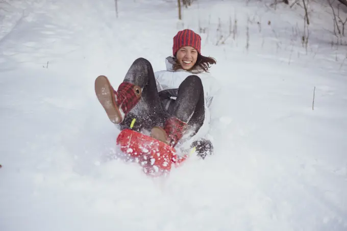 happy European woman laughs and sleds down snow hill in czech republic
