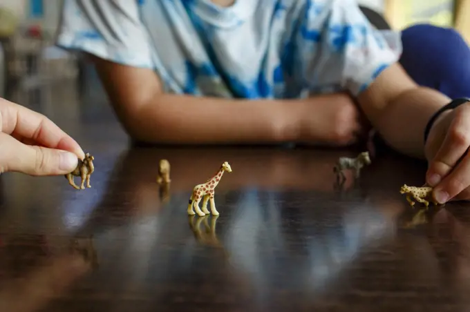 two children play together with miniature toy animals on table