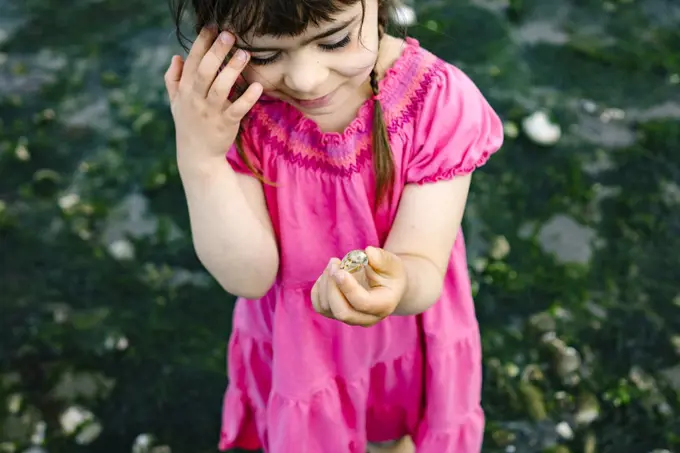 Closeup of a young girl holding a manila clam on the beach
