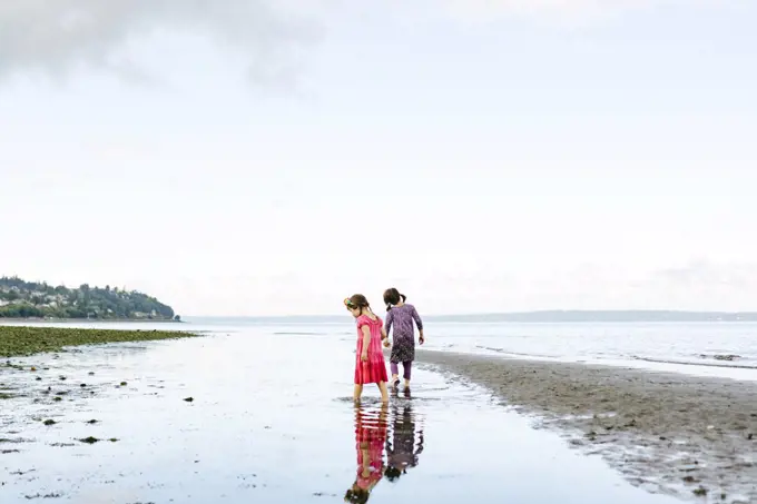 Wide view of two sisters exploring together on the beach