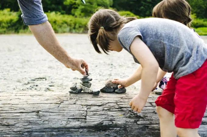 Closeup view of a family stacking rocks together on a beach
