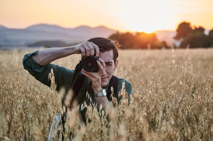 Portrait of a photographer looking at camera in a meadow at sunset