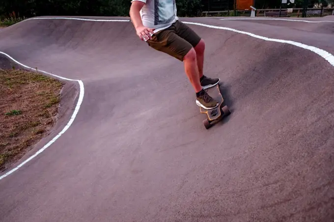 Unrecognizable Young man riding on longboard at the pump track.