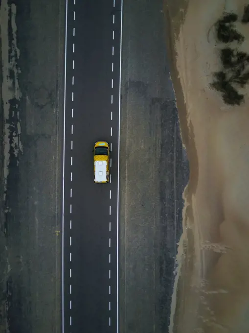 Yellow campervan on empty road by the sandy beach in Netherland,Europe