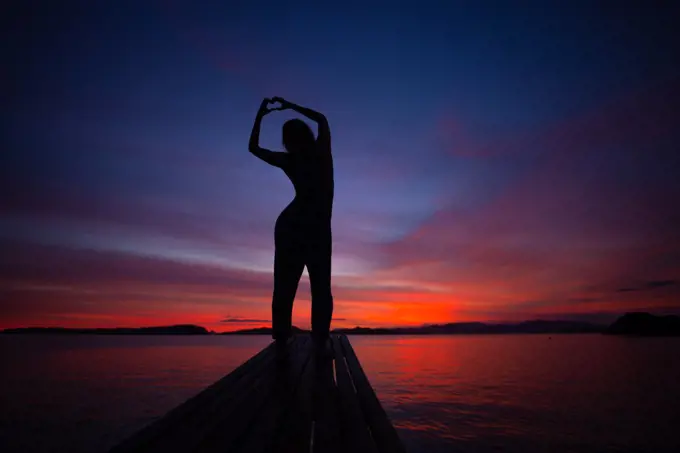 Girl Making A Heart In Front Of Vibrant Sunset In Indonesia
