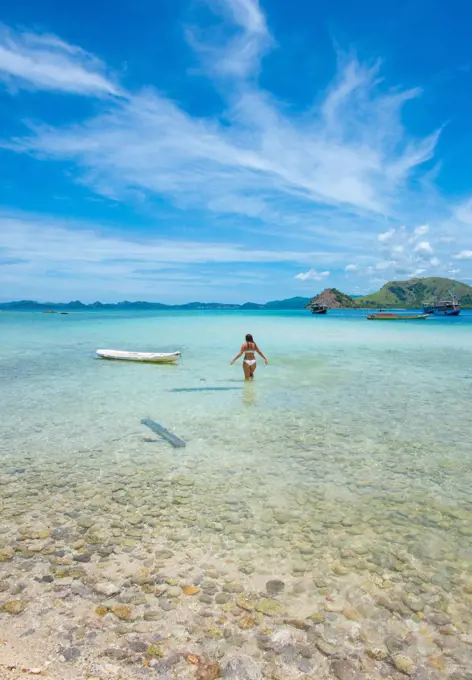 Girl In Paradise Walks Towards White Canoe Off Indonesian Island