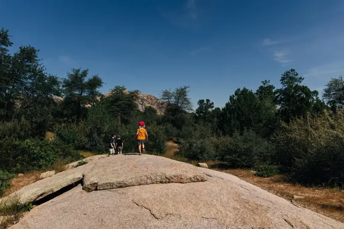 Siblings explore on rock below mountain in forest of Prescott