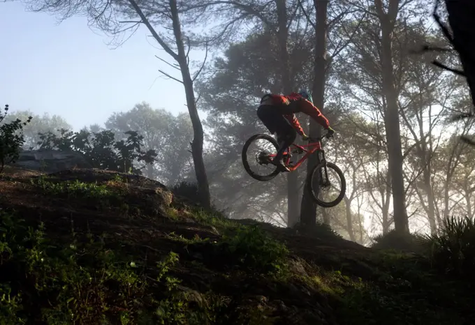 Young mountain biker jumps in a nice foggy morning