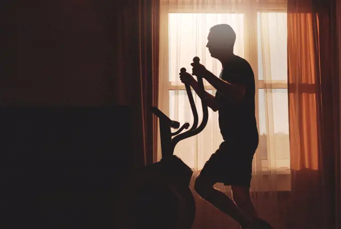A man goes in for sports at dawn at home, silhouette