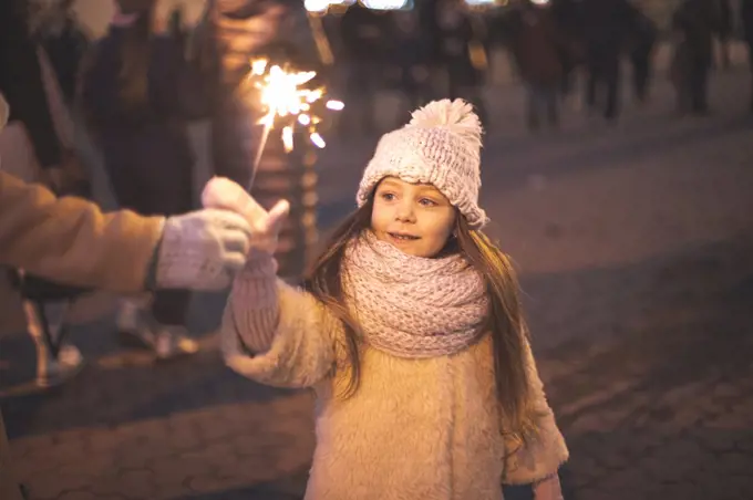 Little girl decorated of ligh and holds burning sparkles