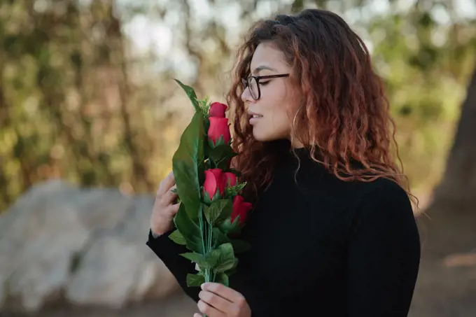 Latin woman with glasses looks lovingly at the roses