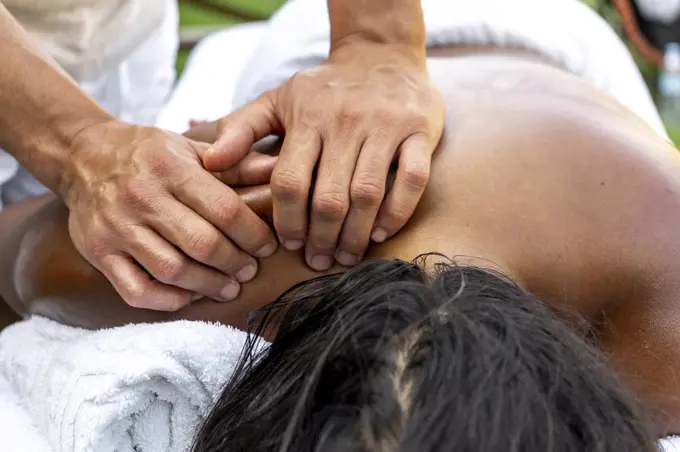 Man's hands massaging multiracial woman's neck