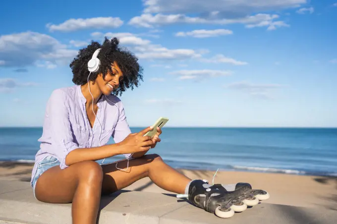 Young woman listening to music on the beach wearing headphones