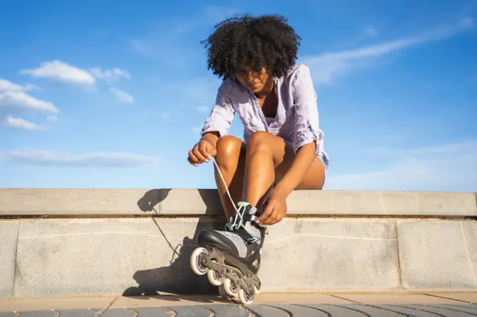 Beautiful young black woman putting on inline skates