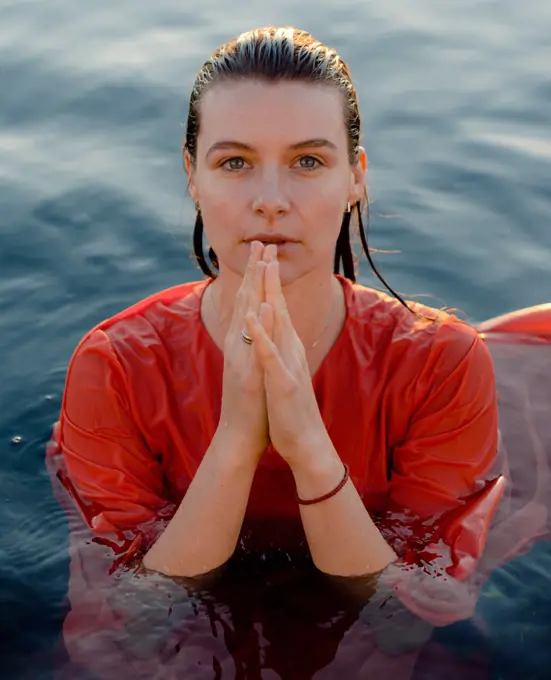 portrait of a woman with blue eyes in a wet orange dress in the water