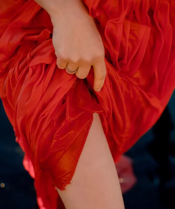 a woman lifts her red wet dress and exposes her legs