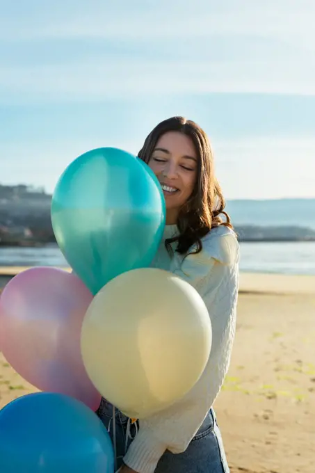 Portrait of a beautiful woman smiling and holding a bunch of balloons