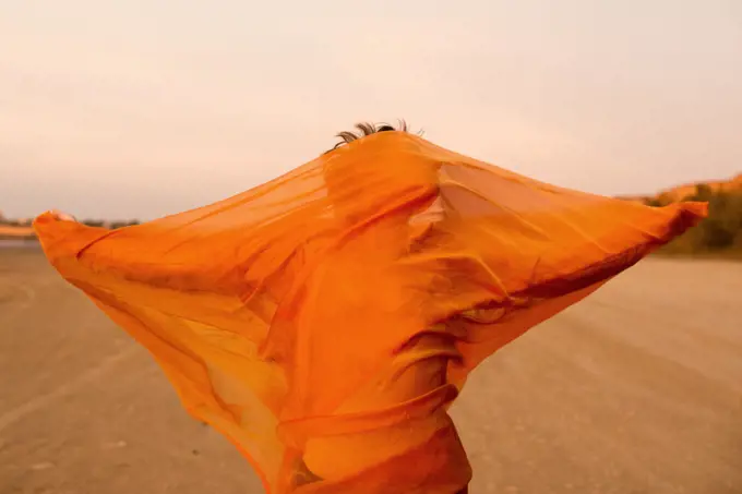 woman with orange cloth in desert with wind