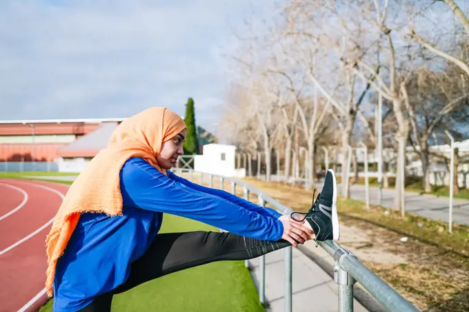 Muslim ethnic woman doing hamstring stretch during workout