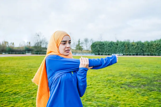 Ethnic female athlete stretching arms before running training