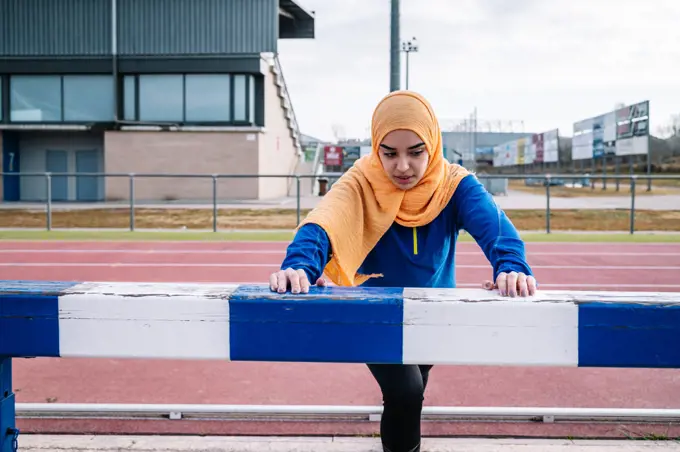 Arab female doing lunge exercise on racetrack